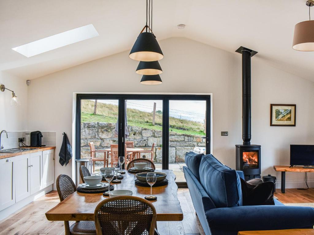 a living room with a table and chairs and a fireplace at Birkshaw Barn in Bardon Mill