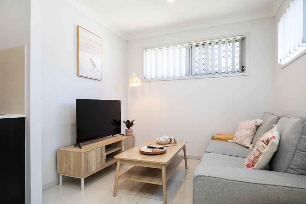 a living room with a couch and a tv at Modern & Beautifully Presented! Close to Transport in Brisbane