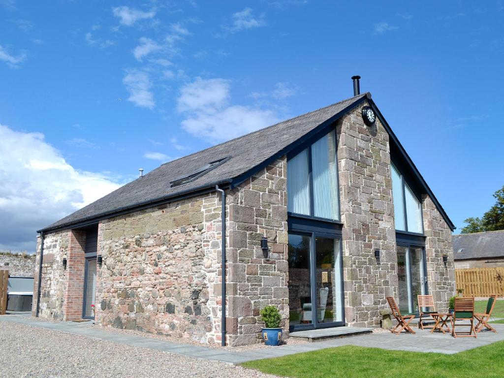 a stone building with a black roof and windows at The Steading in Dubton