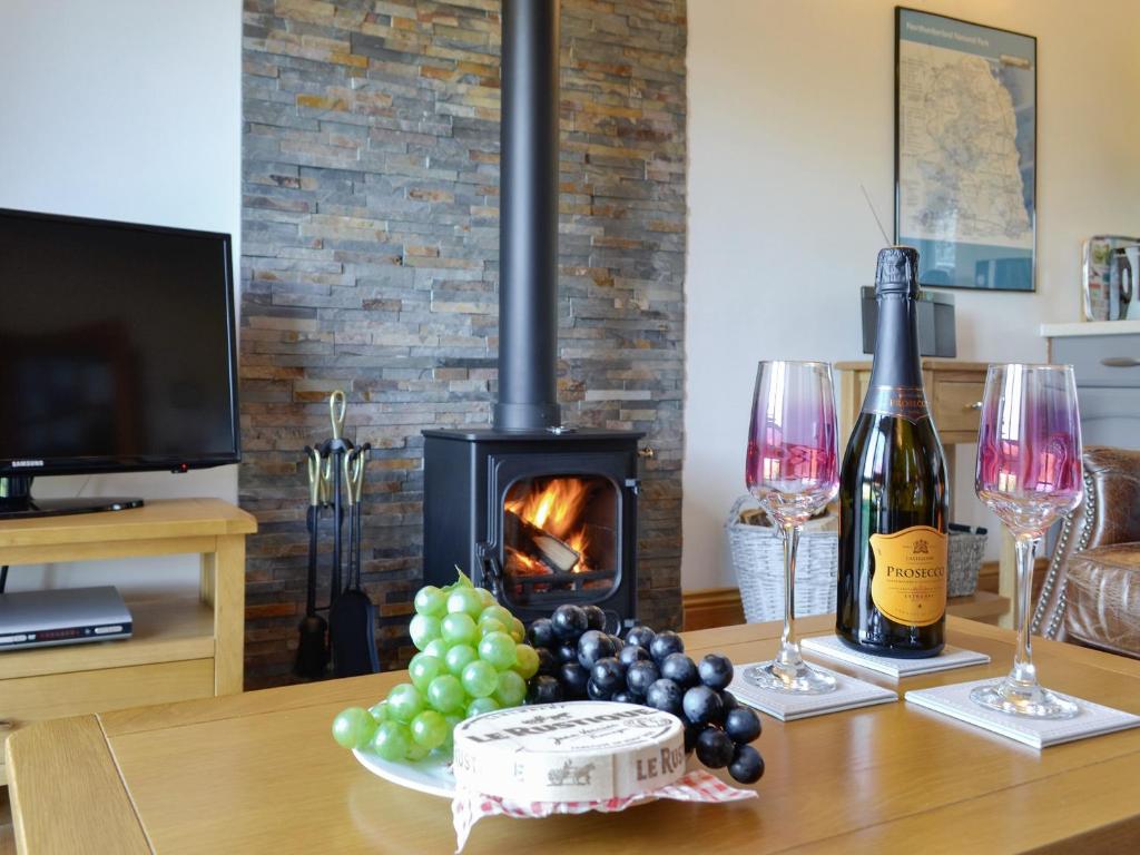 a table with a fireplace with wine glasses and grapes at Stanegate Cottage in Greenhead