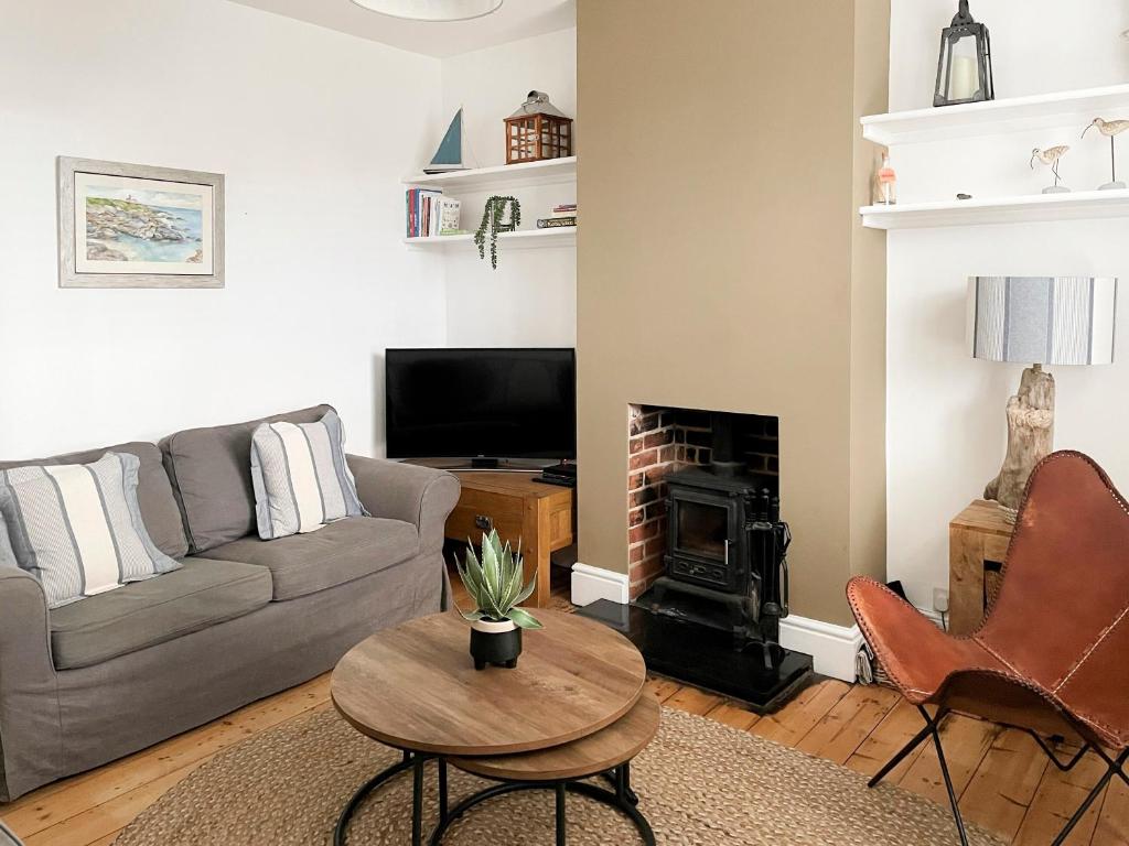 a living room with a couch and a fireplace at Daisy Cottage in Sea Palling