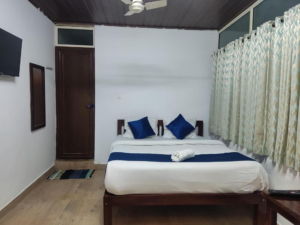 a bedroom with a bed with blue pillows and a window at Lovely Home Stay Munnar in Munnar