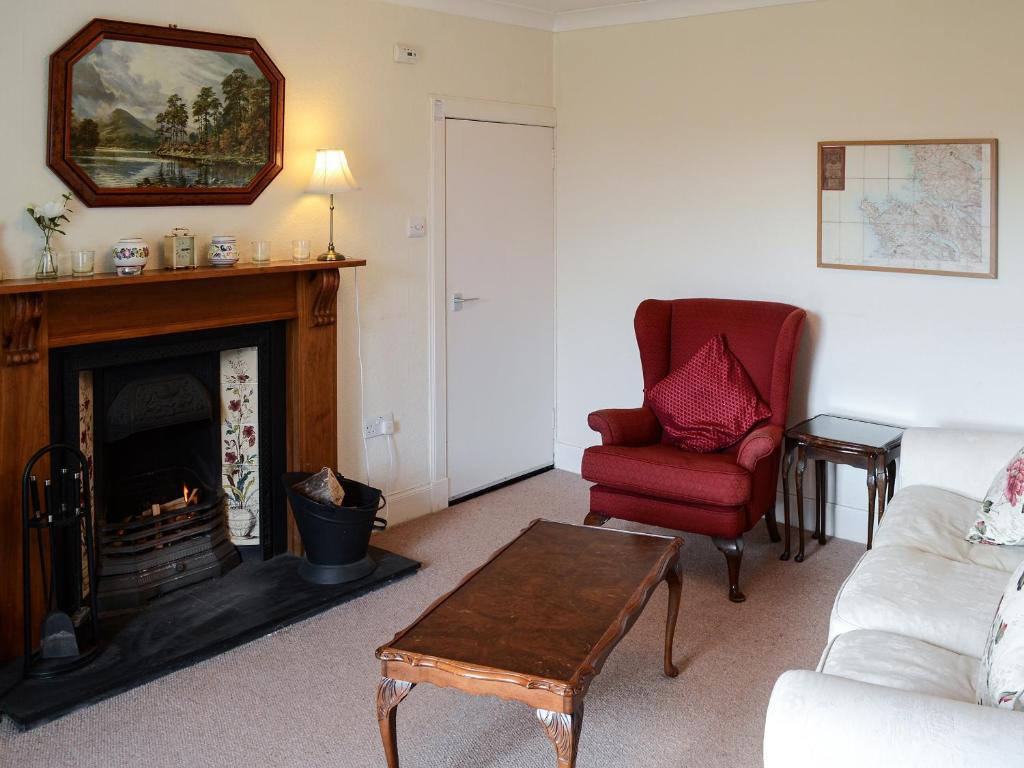 a living room with a fireplace and a red chair at An Sealladh in Lochinver