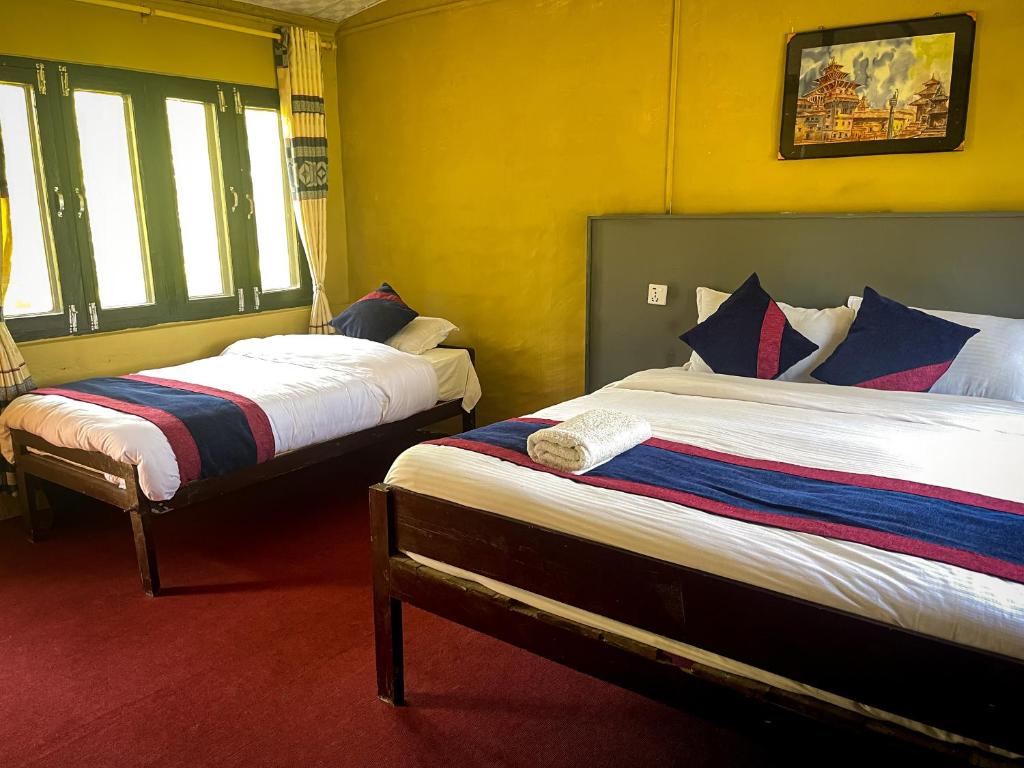 two beds in a room with yellow walls at Hotel Tharu Garden And Beer Bar in Chitwan