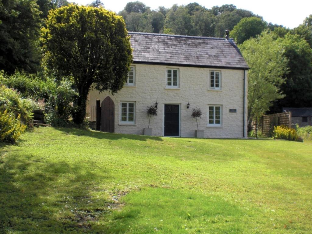 Tintern Abbey Cottage في تينتيرن: منزل أبيض كبير مع ساحة عشبية