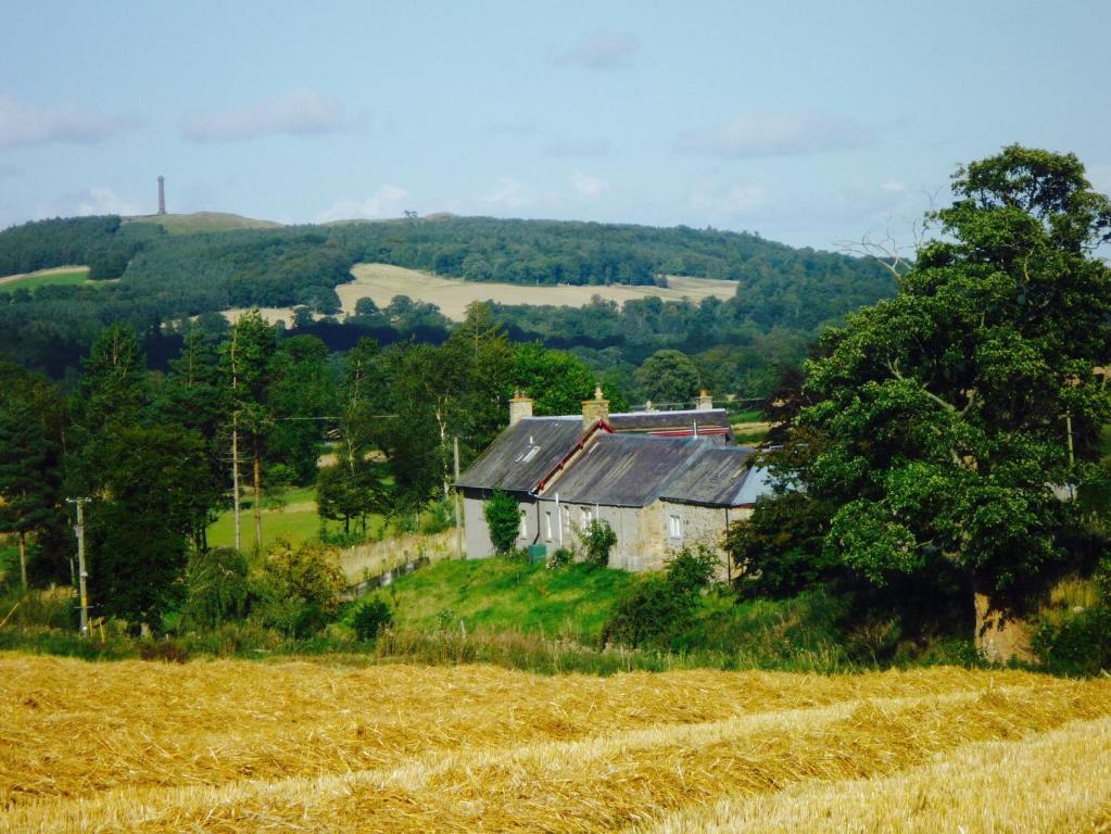 una casa vieja en una colina al lado de un campo en Lantonhall West Wing en Lanton