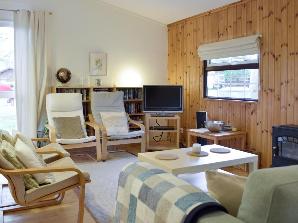 uma sala de estar com um sofá e cadeiras e uma televisão em Oak Haven em Cenarth