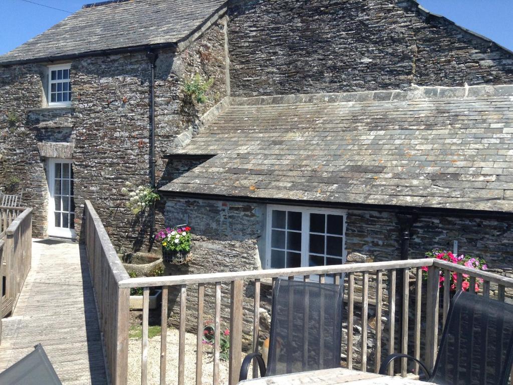 an old stone building with a fence and flowers at Purlinney in Treknow