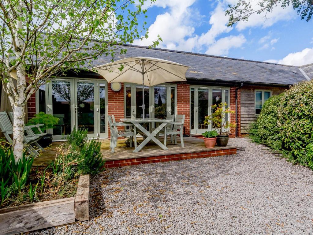 a brick house with a patio with an umbrella at Primrose in Shepton Mallet