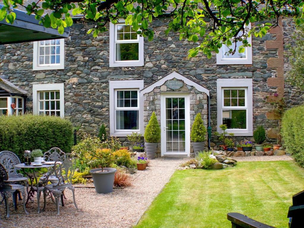 un jardin en face d'une maison en pierre dans l'établissement Apple Tree Cottage, à Bassenthwaite