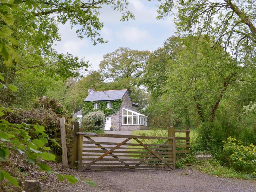 a house behind a wooden fence with a gate at Quarrymans Cottage in Linkinhorne