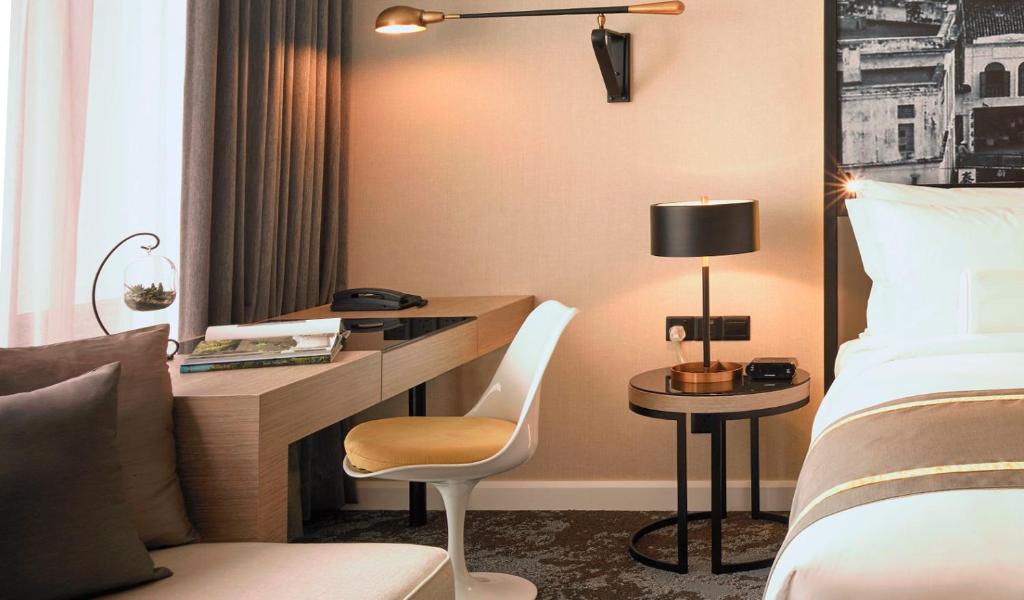 a hotel room with a desk and a bed at Hotel Stripes Kuala Lumpur, Autograph Collection - TravelEase Visa-Free Getaway in Kuala Lumpur
