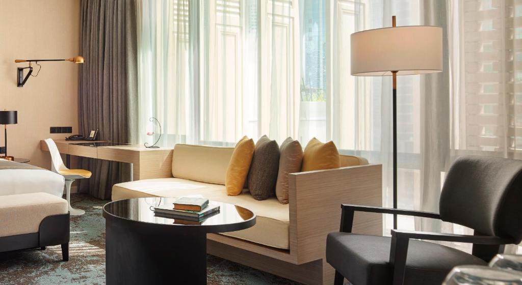 A spacious-looking sitting area facing tall windows, with a sofa and writing desk.