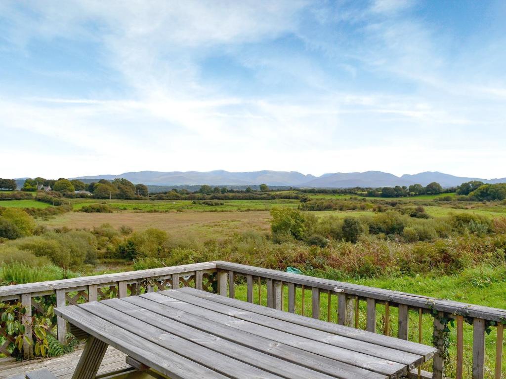 un banc en bois assis sur une terrasse donnant sur un champ dans l'établissement Pant Y Mel, à Brynteg