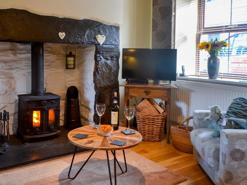 a living room with a fireplace and a table with wine glasses at Eirianfa in Penmachno
