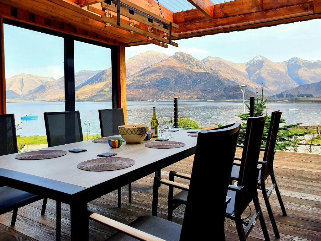 a dining room table with a view of a lake at Ratagan Lodge in Kintail
