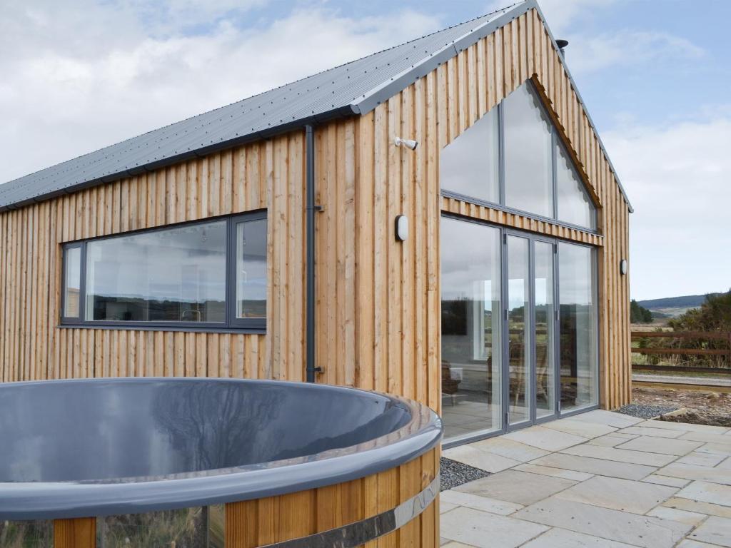 un edificio de madera con bañera delante en Muirtown Lodge, en Newmill