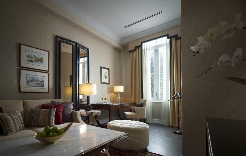 A traditionally styled sitting room with a marble coffee table, desk and tall window.