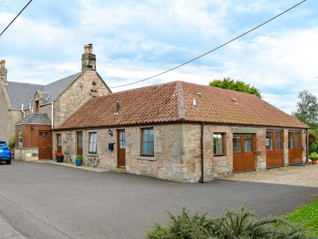 an old stone building with a red roof at The Cottage At Cauldcoats in Linlithgow