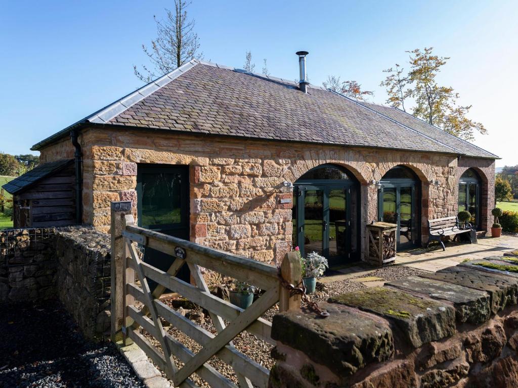 a stone building with a fence in front of it at Cart Shed in Mauchline