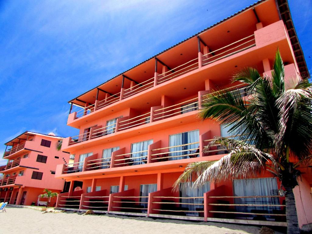 um edifício laranja na praia com uma palmeira em Hotel El Murique em Zorritos