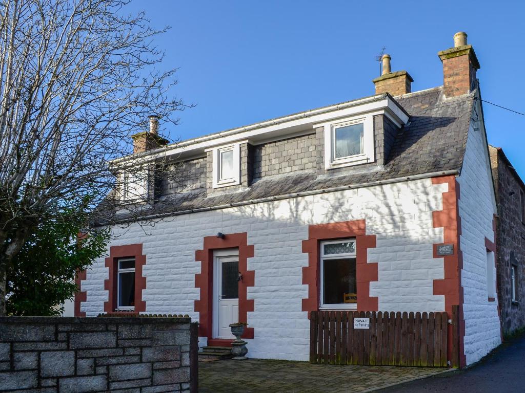 a white house with red and white brick at Larch Cottage in Blairgowrie