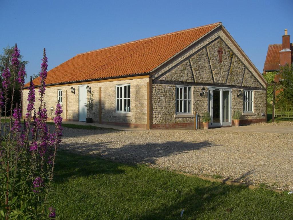 an old stone building with a red roof at Honeysuckle Cottage in Oasby