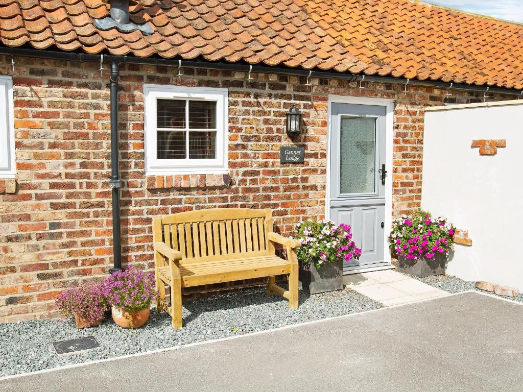 a wooden bench sitting in front of a brick house at Gannet Lodge - Uk30977 in Bempton