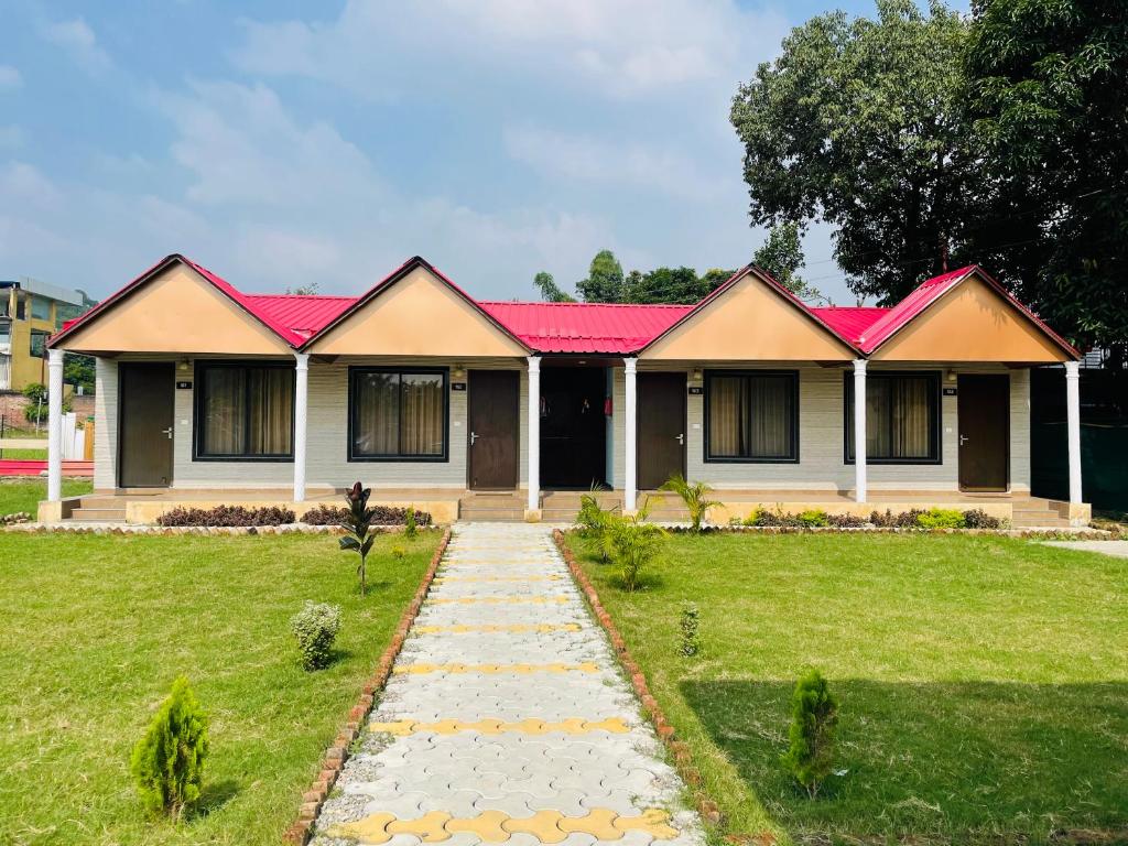 una casa con techo rojo y pasarela en The Deerfield Cottages, en Rāmnagar