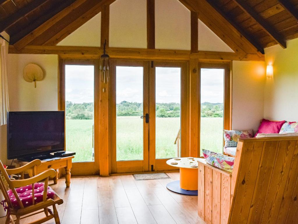 a living room with sliding glass doors and a television at The Long Barn in Little Baddow