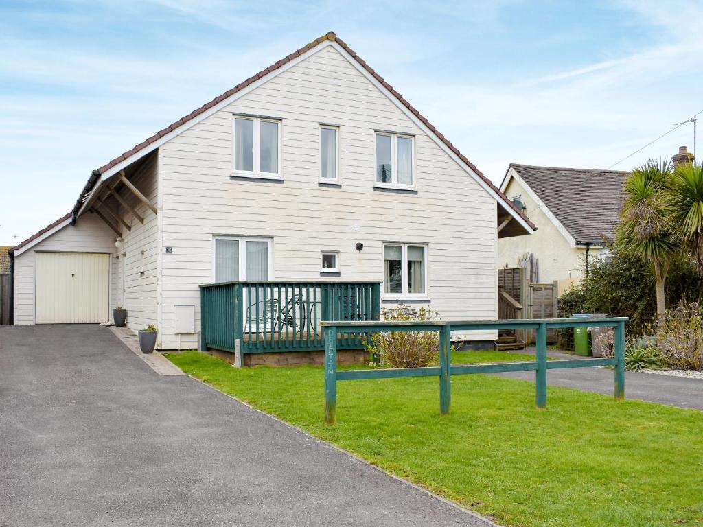 a white house with a green fence in front of it at Drift In in Yapton