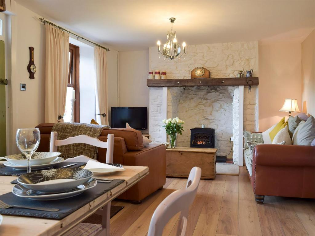 uma sala de estar com uma mesa e uma lareira em Moss Cottage em Burry Port