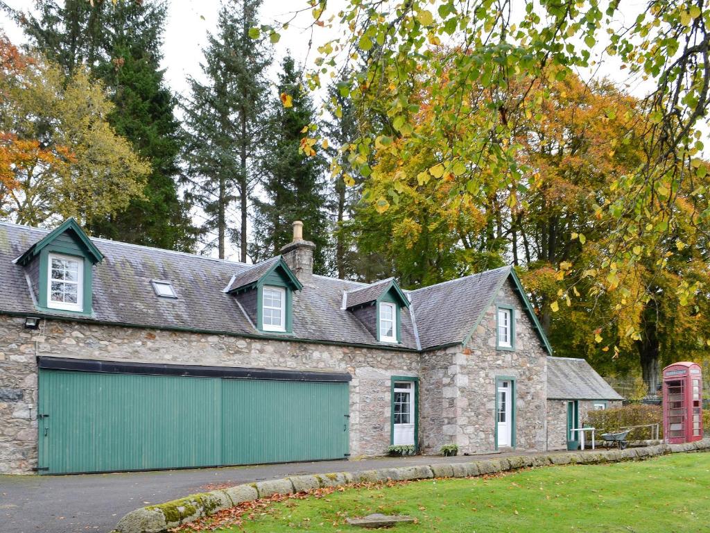 una casa de piedra con un garaje verde en Inverchroskie Cottage, en Enochdhu