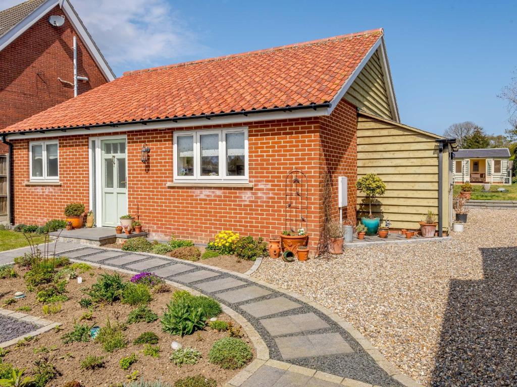 a red brick house with a garden in front of it at Holly Lodge in Hemsby