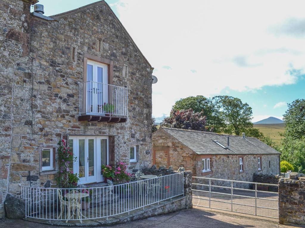 a stone house with a balcony and a fence at Rambling Rose- Lwg in Ireby