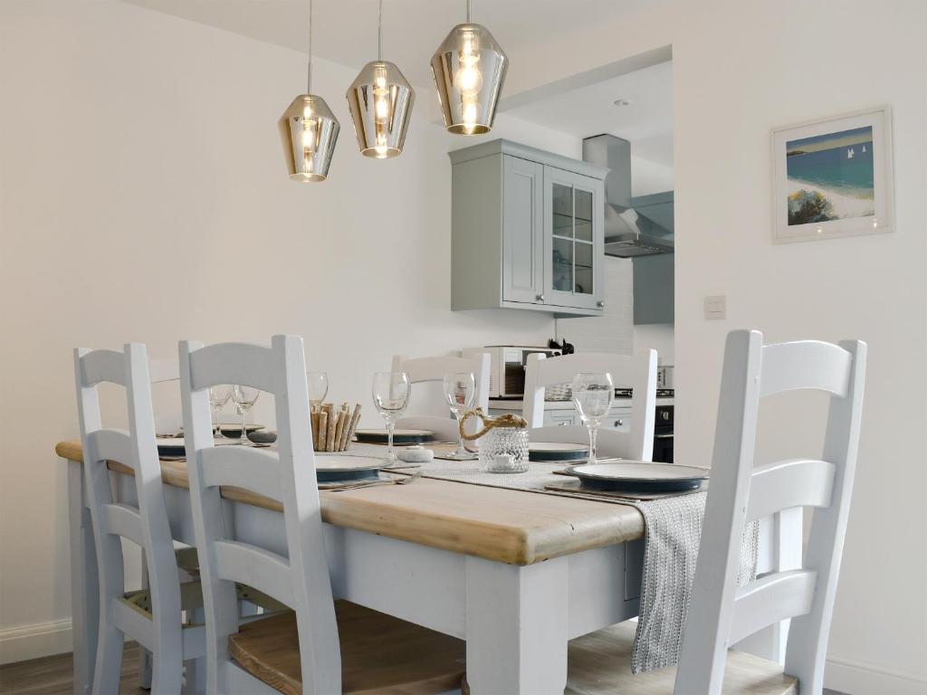 a white dining room with a table and chairs at Sapphire Cottage in Pakefield