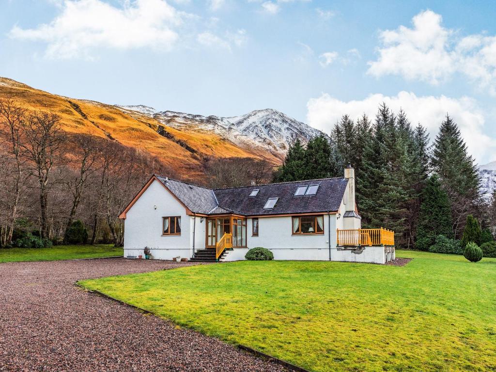 a white house with a mountain in the background at Bidean Lodge in Glencoe