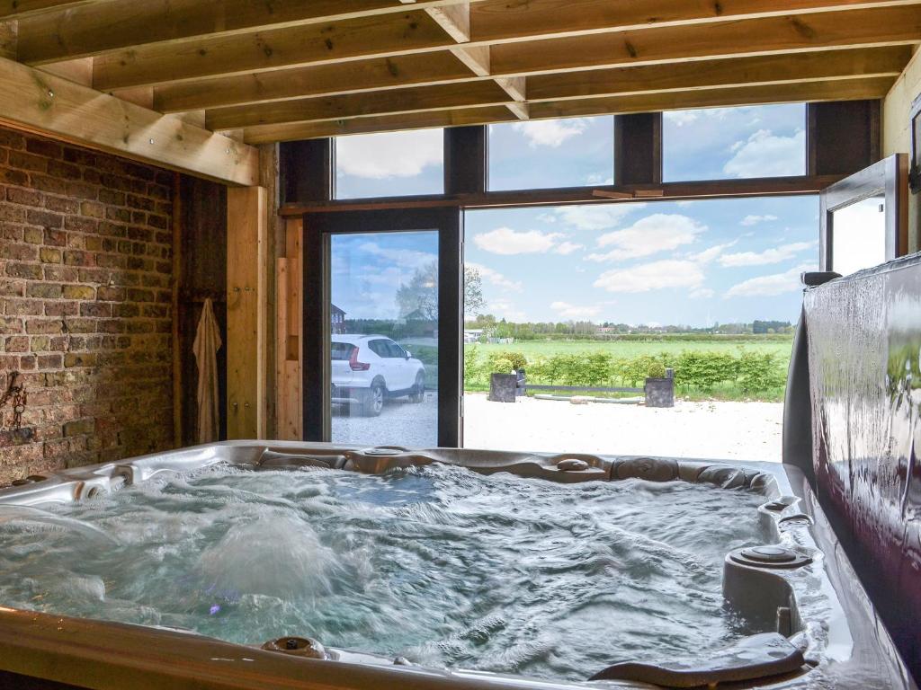 a hot tub in a room with a large window at The Old Stables in Tickton