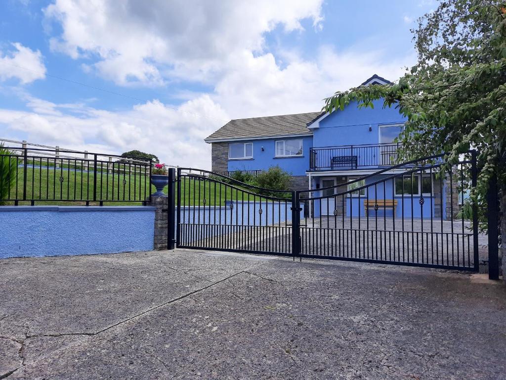 a black gate in front of a blue house at Marlais View in Llansadwrn