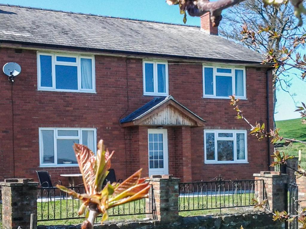 a red brick house with blue windows at Garth Ucha in Llanyblodwel