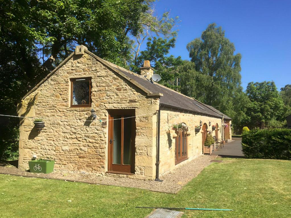 an old stone building with a grass yard at Rivers Edge Cottage in Shotley Bridge