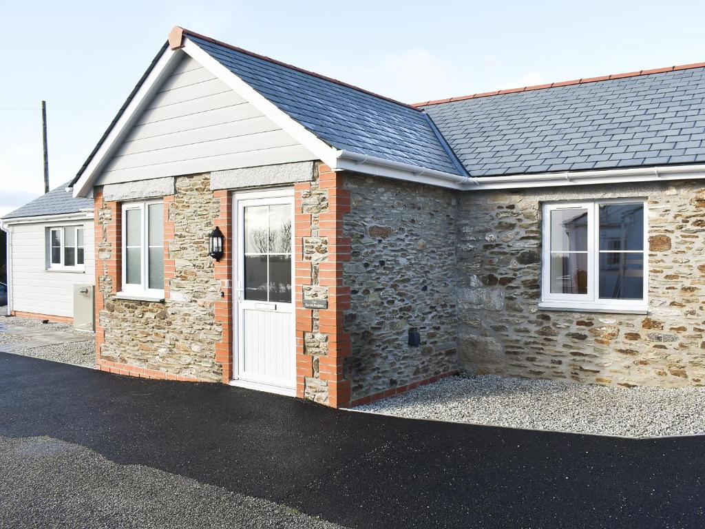 a brick house with a white door on a street at Four Burrows Bungalow in Chacewater