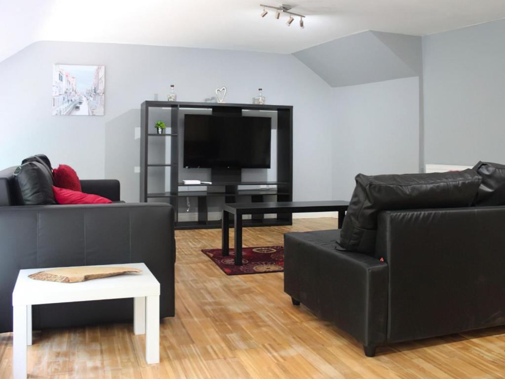 a living room with two black couches and a flat screen tv at Riverside Penthouse - Uk31551 in Matlock