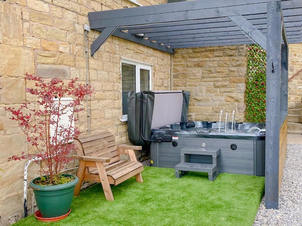 a backyard with a grill and a bench and a chair at Boundary Cottage in Unstone