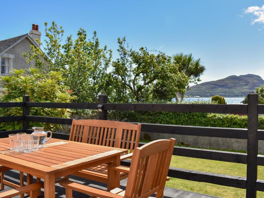 a wooden table and chairs on a deck with a view of the ocean at Anchorage Cottage in Lamlash