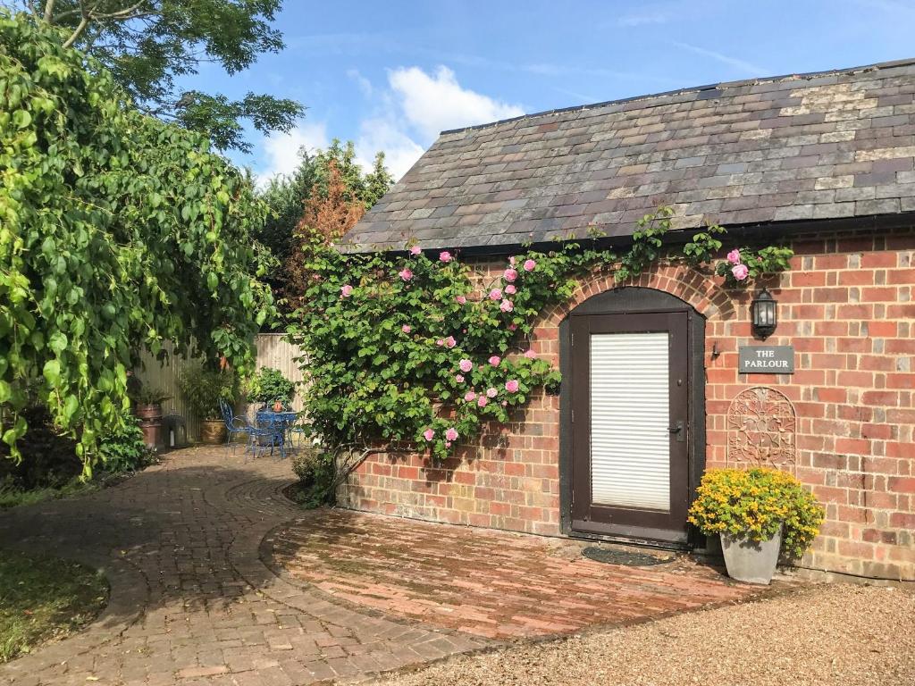 un edificio de ladrillo con una puerta y flores en The Parlour en Hadlow Down