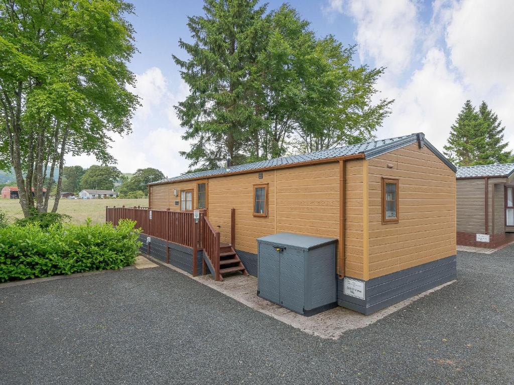 a small wooden building with a trash can in a parking lot at Ochil View Lodge in Dollar