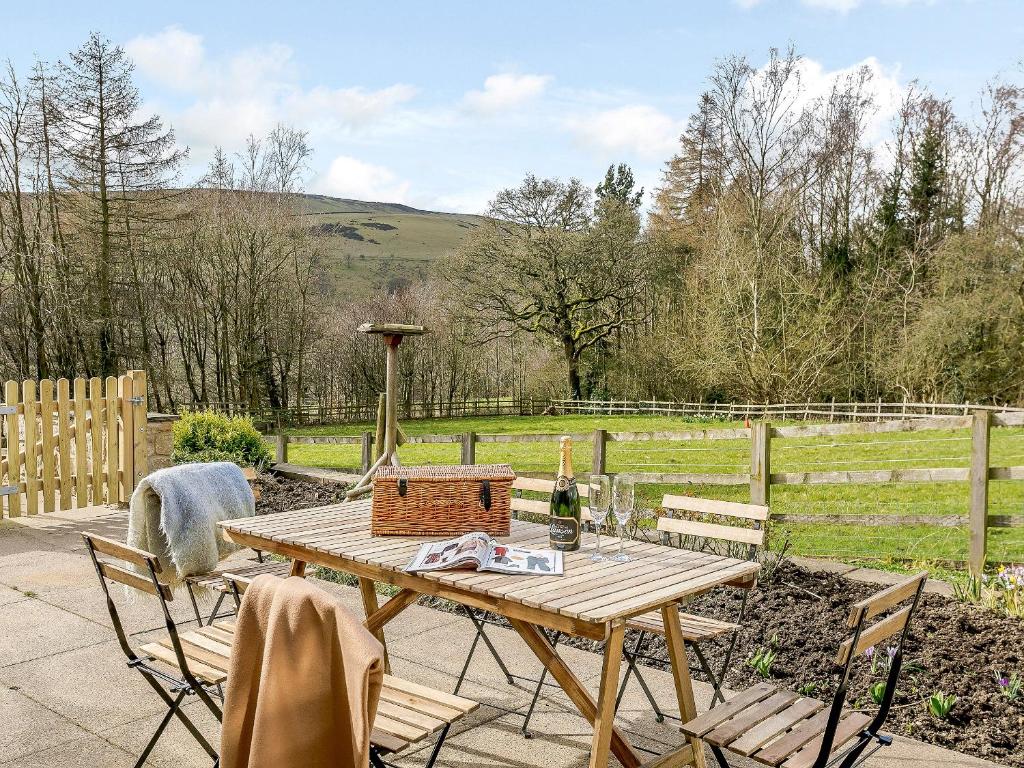a picnic table with a bottle of wine and chairs at Cunliffe Cottage in Hathersage