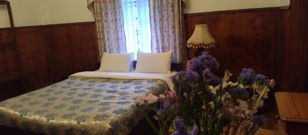 a bedroom with a bed with a window and purple flowers at The Trevene Hotel in Nuwara Eliya