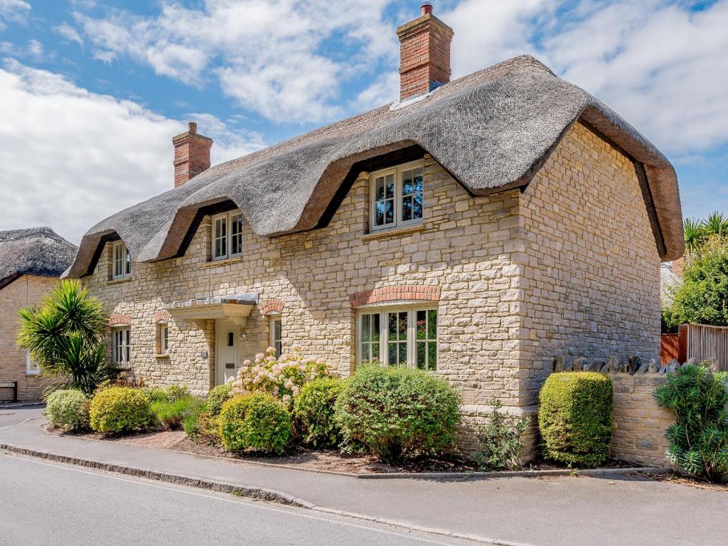 a large stone house with a thatched roof at Hambury House in West Lulworth